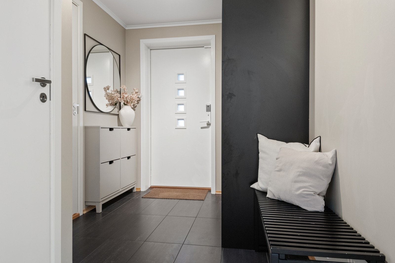 Entreen er innbydende med grå fliser på gulvet, lysmalte, glatte veggflater og hvitmalt himling. Galleribilde