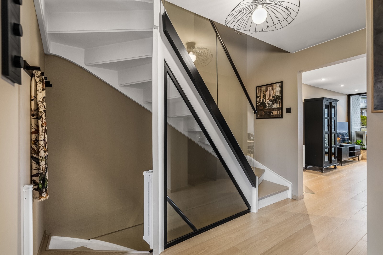 Elegant trappeløsning med stilrent glassrekkverk og moderne sorte innramminger. Galleribilde