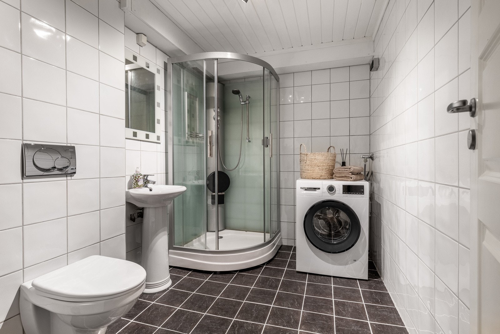 Praktisk baderom i kjeller benyttet som vaskerom. Galleribilde