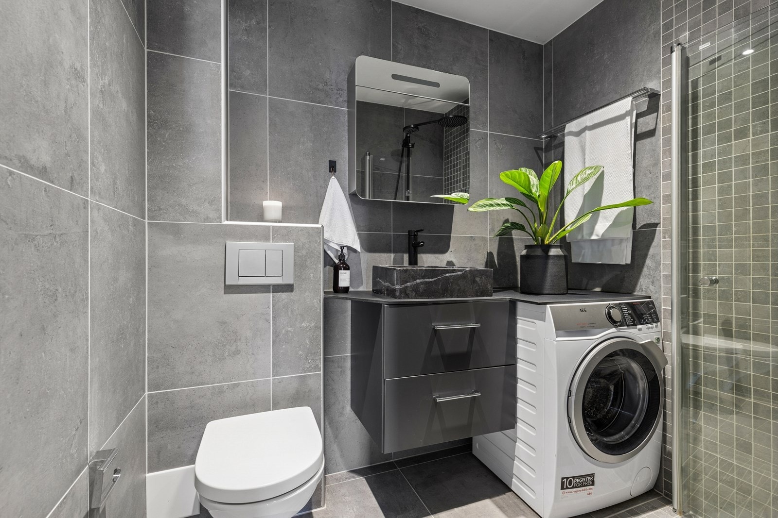 Lekkert og moderne bad som er innredet med dusjhjørne, vegghengt toalett og opplegg for vaskemaskin. Denne medfølger ved salg! Galleribilde