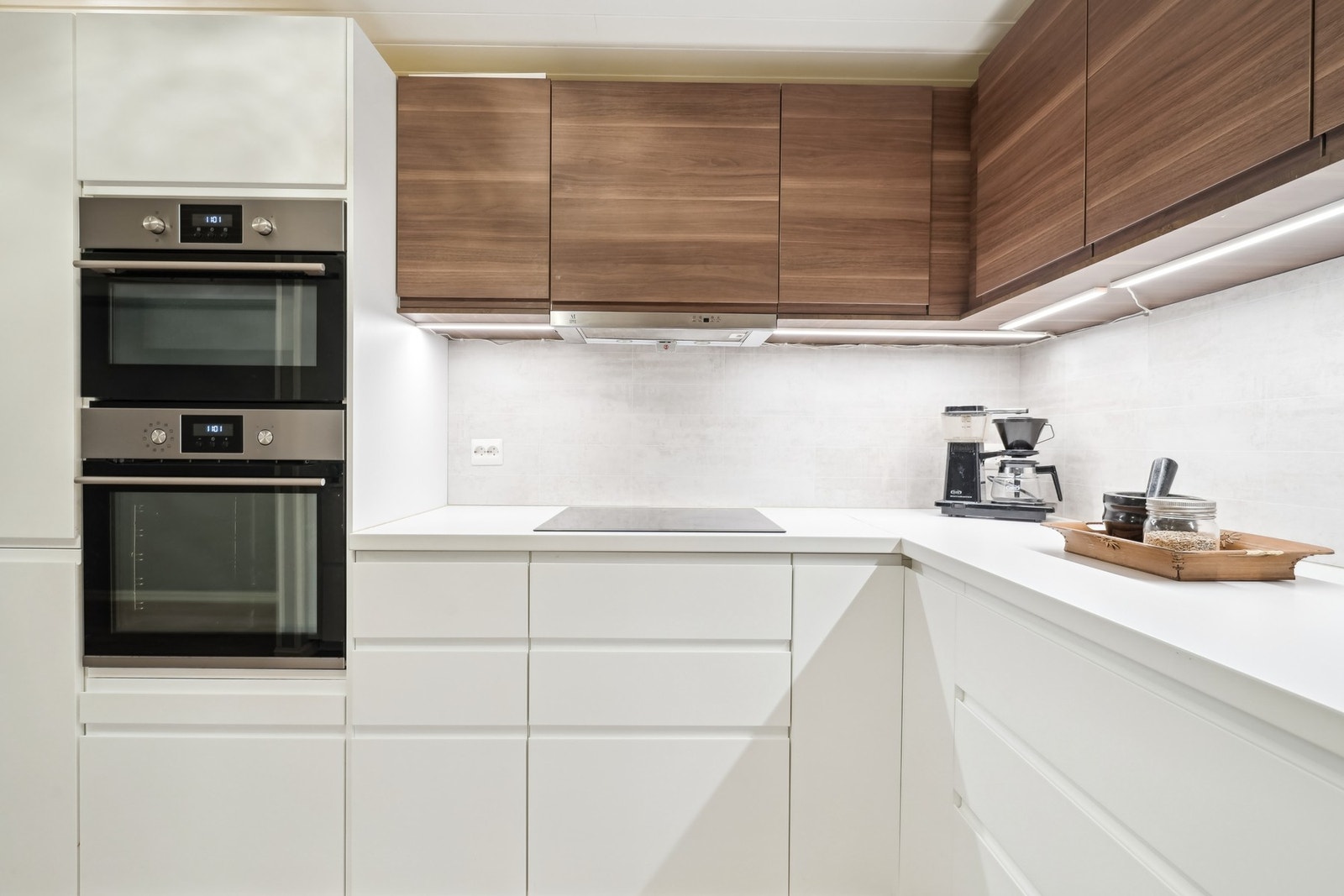 Kjøkkeninnredening fra IKEA med hvite og mørke, glatte fronter. Kjøkkenet er utstyrt med integrerte hvitevarer som stekeovn, mikrobølgeovn, platetopp, kjøleskap og oppvaskmaskin. Galleribilde