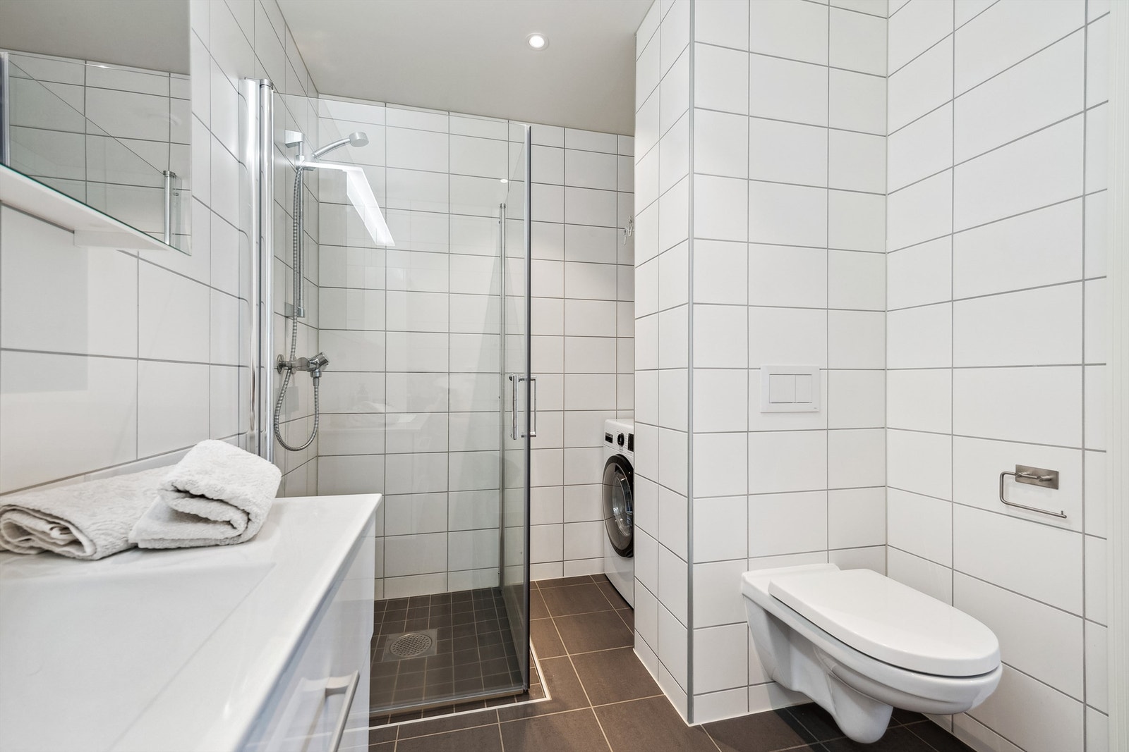 Badet er i god størrelse med vegghengt servantinnredning, veggskap og speil med lys. Dusjhjørne med dusjvegger. Det er opplegg for vaskemaskin. Galleribilde