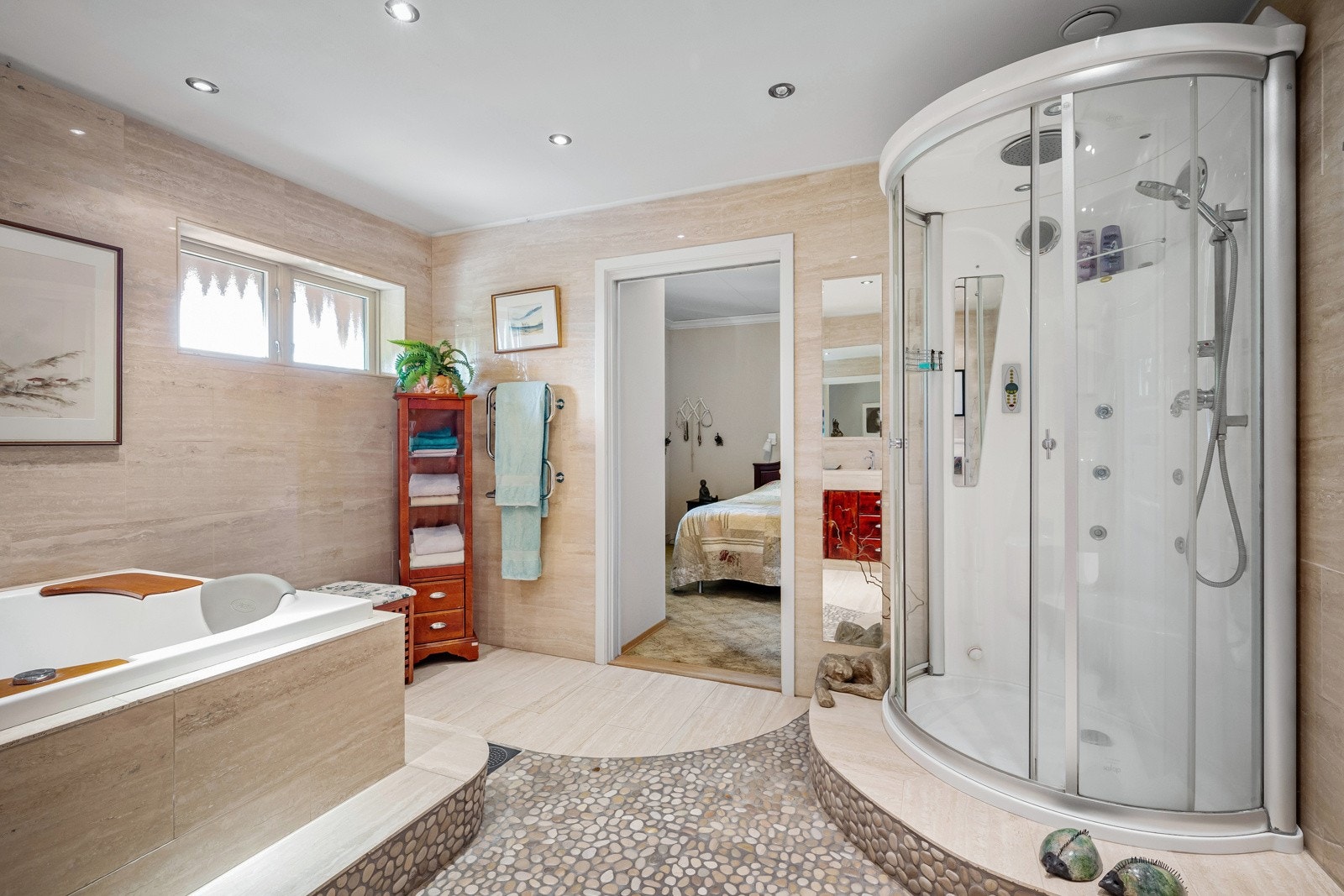 Badet er innredet med dusjkabinett, stort innmurt spabadekar, vegghengt toalett med wash&clean, plassbygd servantinnredning som er flislagt og nedfelt porselensvask. Galleribilde