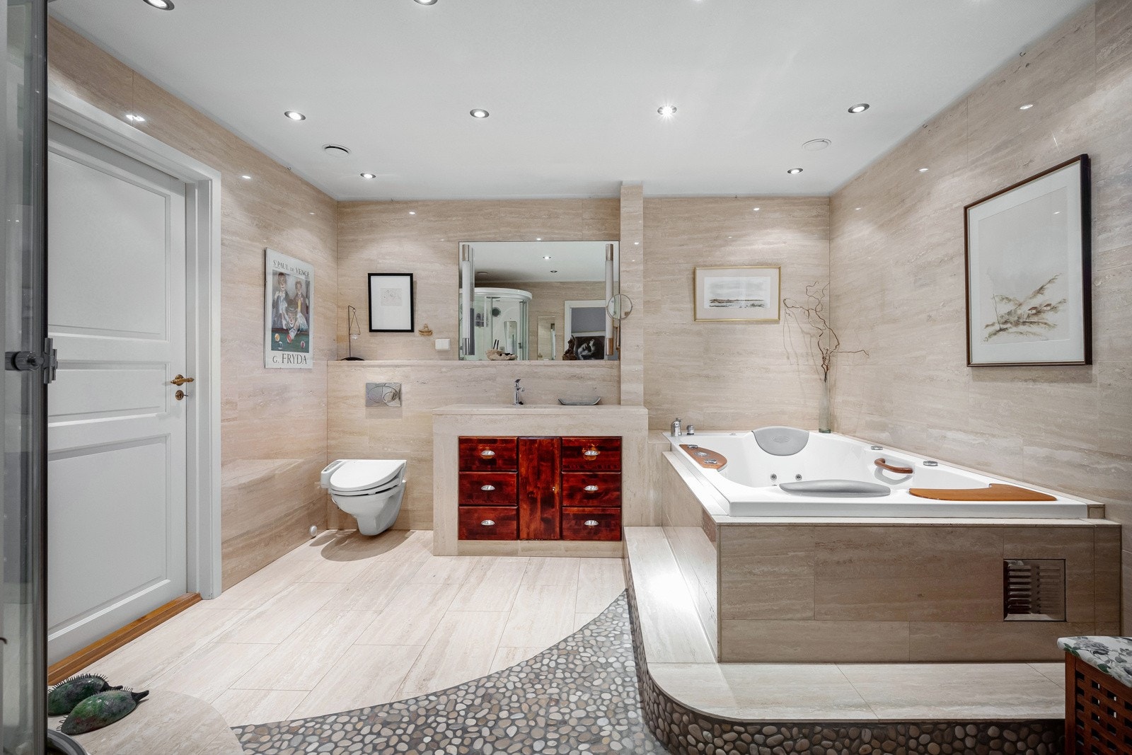 Bad med flislagte overflater av lekre marmorfliser, samt gulvvarme og taket er av malt tapet og innfelt downlights. Galleribilde