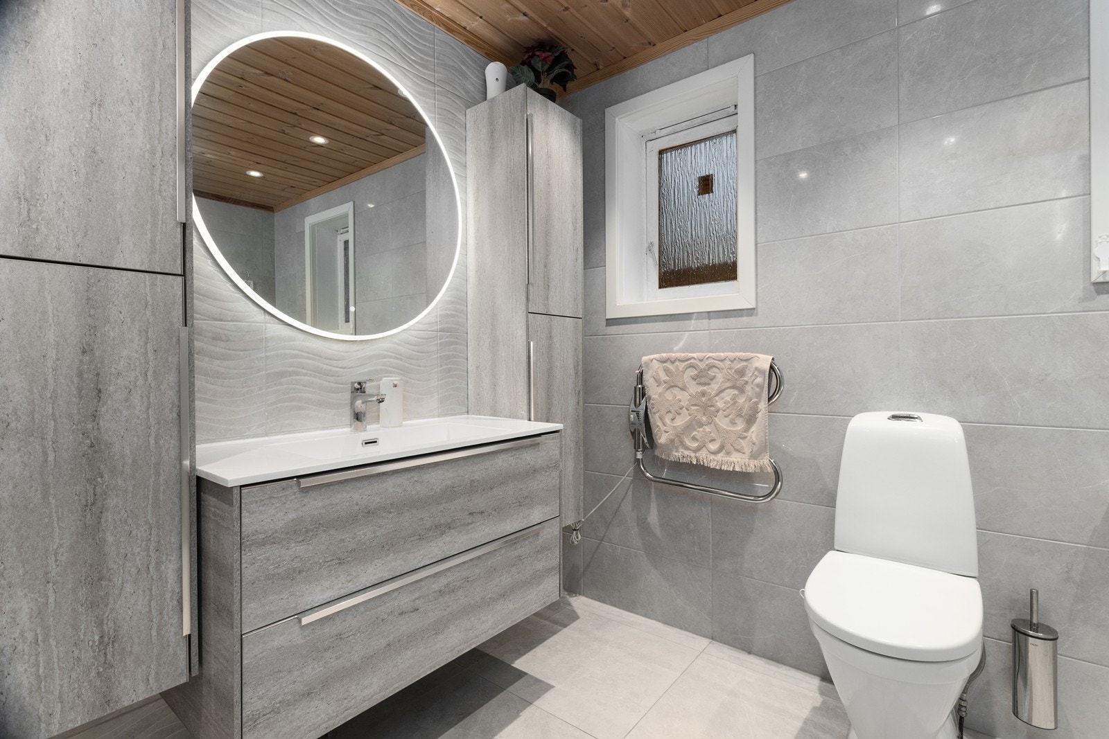 Tidløst bad i nøytrale farger og materialer. Gulv og vegger er flislagt, og rommet varmes opp med elektriske varmekabler. Galleribilde