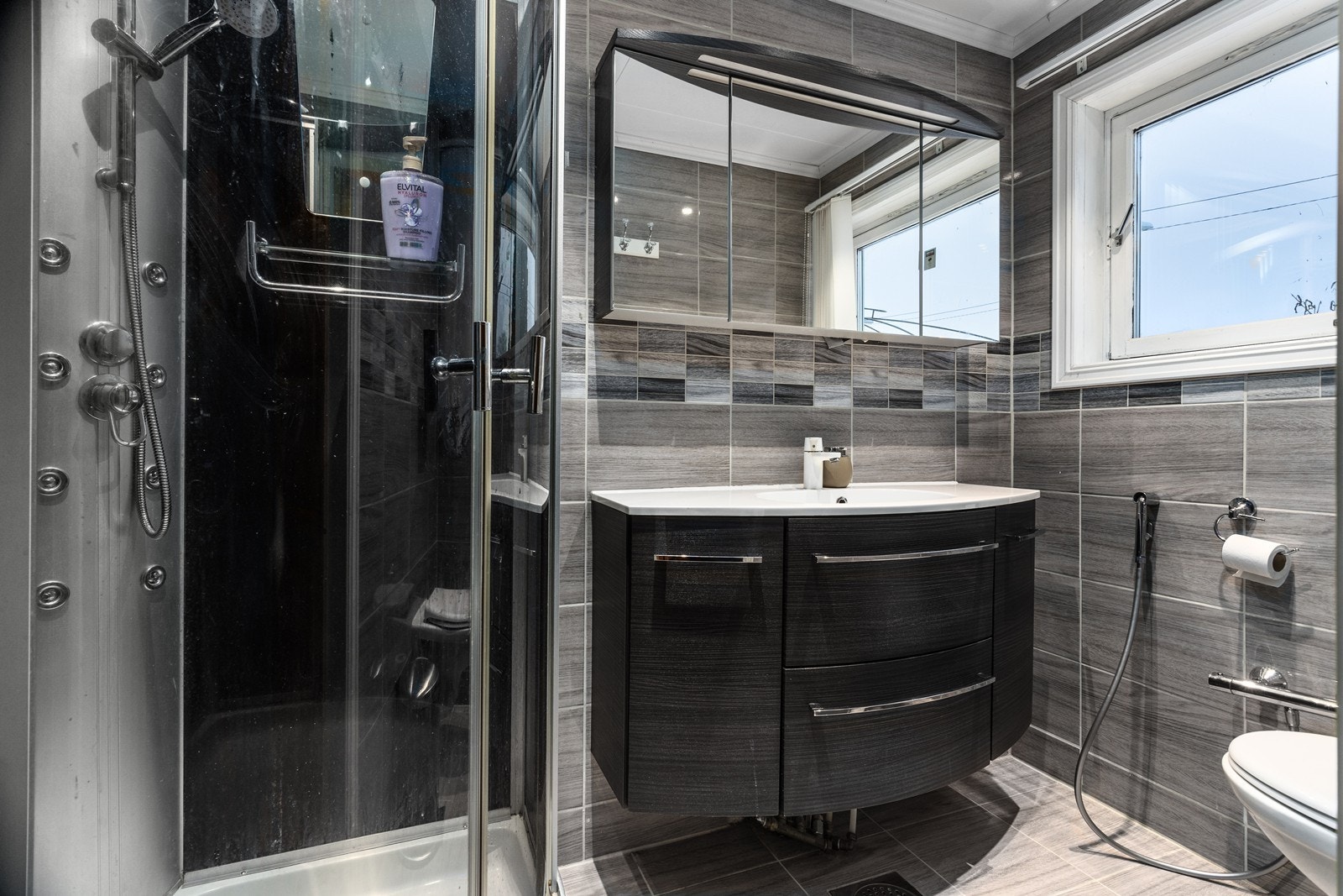 Boligen har to bad, hvor det ene ligger i 1. etasje og er innredet med innredning med servant, veggskap med speil og belysning, dusjkabinett og toalett. Galleribilde