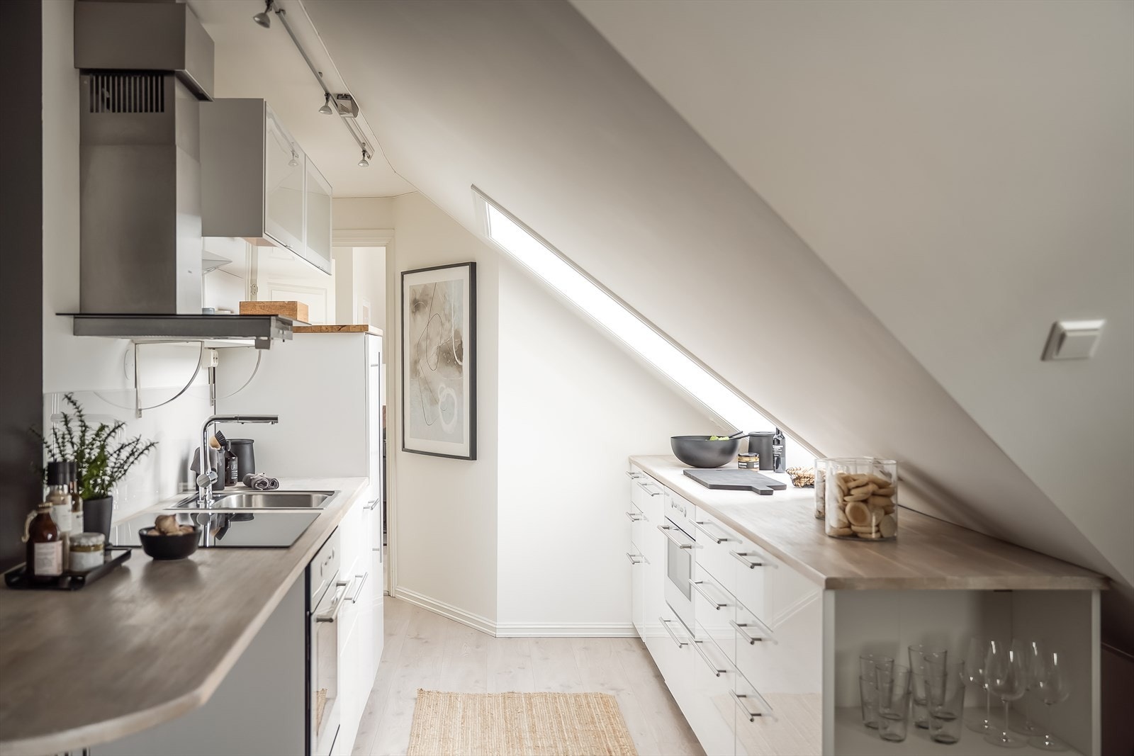 Stilfullt kjøkken med slette og lyse fronter og heltre benkeplate. Galleribilde