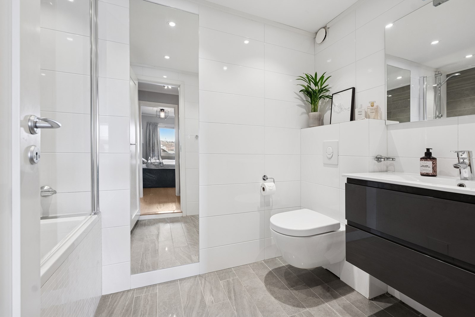 Her er det dusj i innfliset baderkar, veggfestet klosett, servant, benkeskap med glatte fronter, samt speil og belysning over servant. Galleribilde