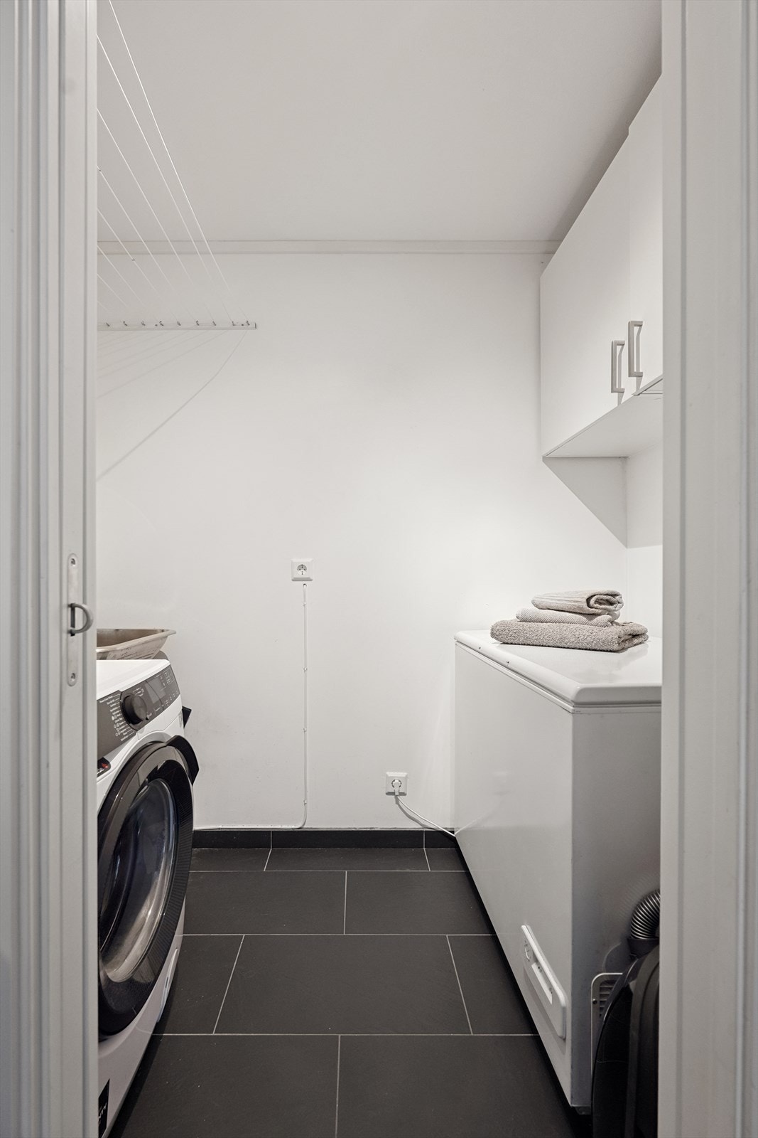 Boligen har en innvendig bod ved kjøkkenet. Boden er praktisk tilrettelagt og brukes som vaskerom. Rommet har flislagt gulv, opplegg for vaskemaskin, utslagskum i rutfritt stål samt overskap med glatte fronter. Galleribilde