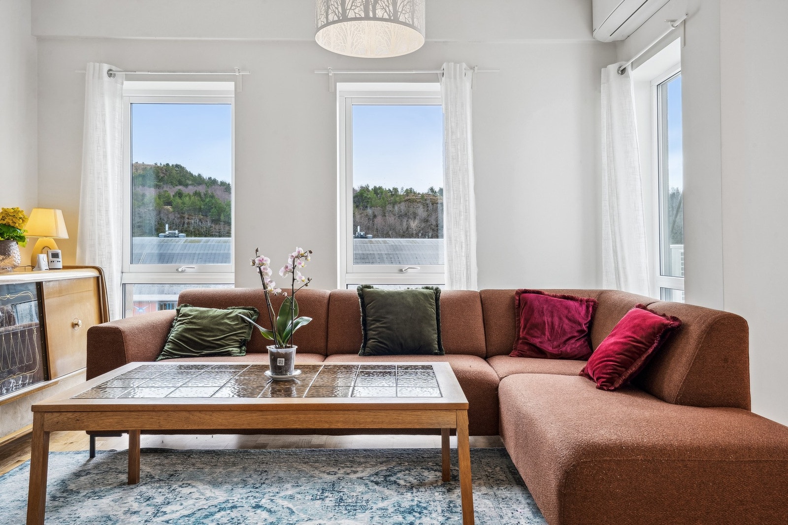 Lys og moderne stue med store vinduer som slipper inn rikelig med dagslys. Galleribilde