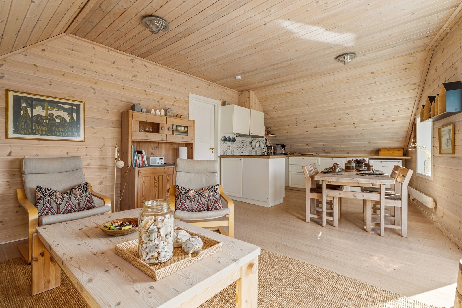 Lyst og trivelig stue og kjøkken med åpen løsning. Stort vindu mot havna og takvindu gir mye lys og flott utsikt. Gjennomført hytte preg med panel i tak, vegger og furu gulv. Galleribilde