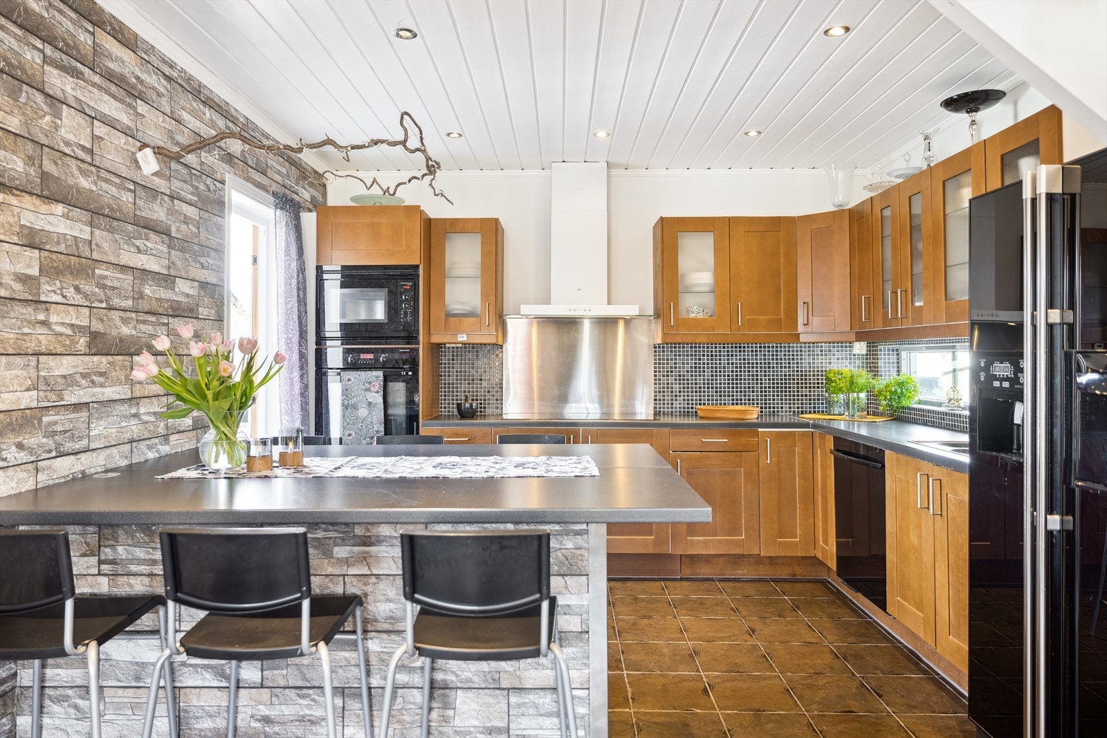 Entreen glir sømløst over i et stort kjøkken, der en smart barløsning markerer overgangen mellom sonene. Galleribilde