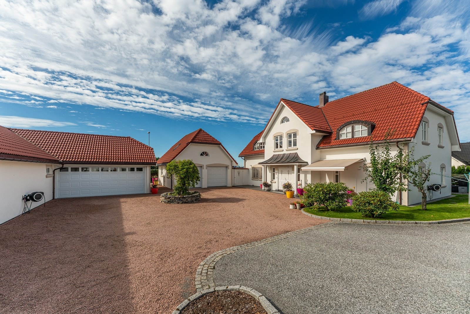 Flat innkøyring til skjerma tun med to garasjer og inngangspartiet Galleribilde