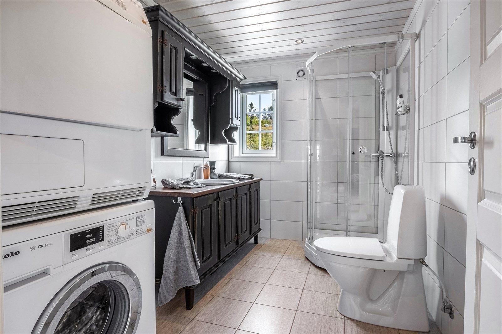 Det største badet har lyse, flislagte overflater, varme i gulvet og downlights i himling. På badet er det også opplegg for vaskemaskin og tørketrommel. Galleribilde