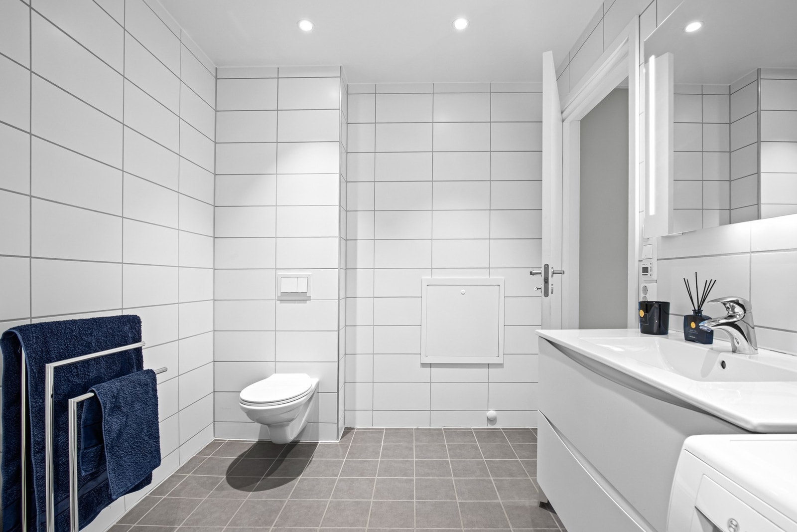 Badet er utstyrt med veggmontert toalett, nedsenket dusjhjørne med innfellbare glassdører og opplegg for vaskemaskin. Galleribilde
