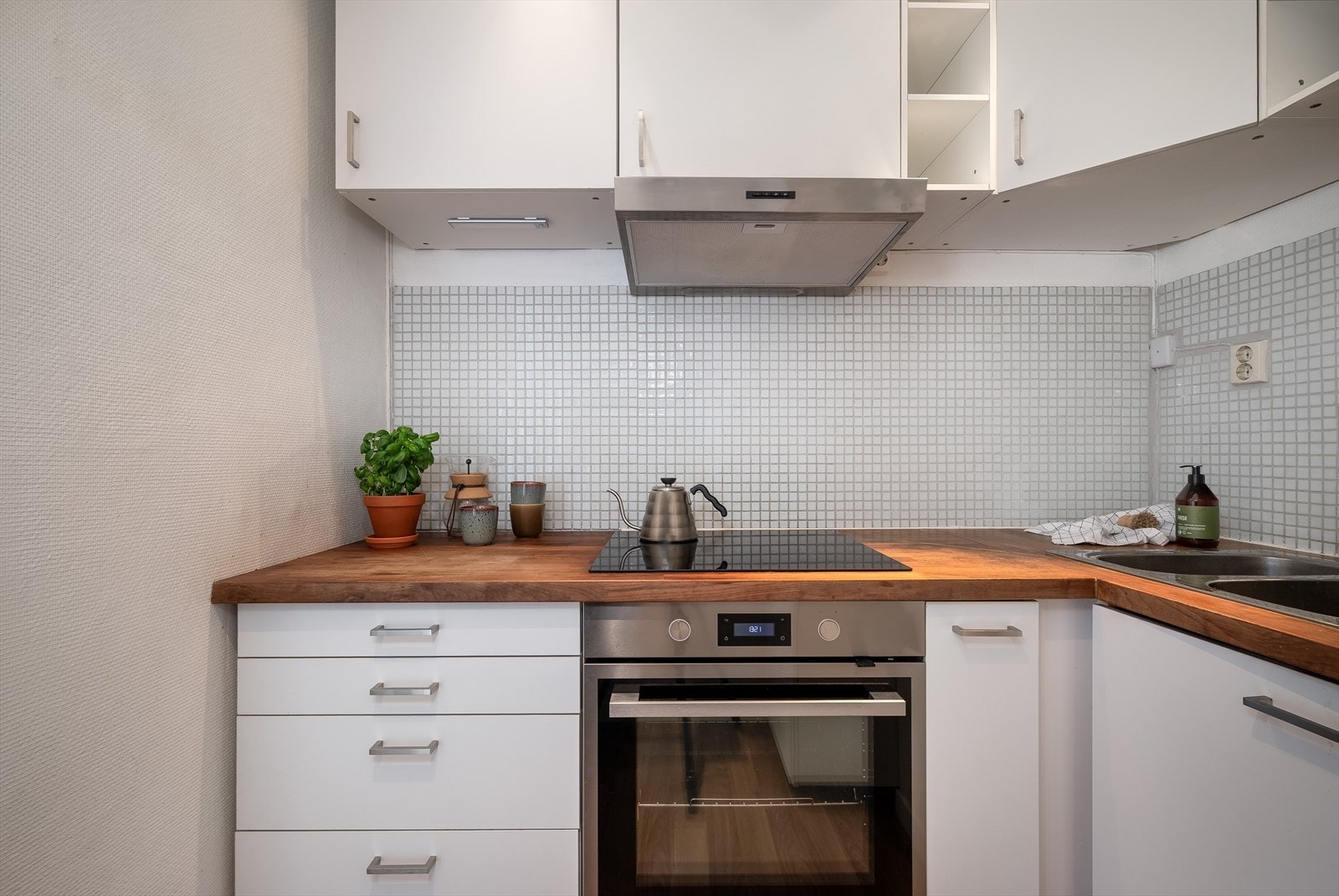 Innredningen består av hvite glatte fronter, benkeplater i tre/spon, rustfri oppvaskkum, ventilator med kullfilter og integrerte hvitevarer. Galleribilde