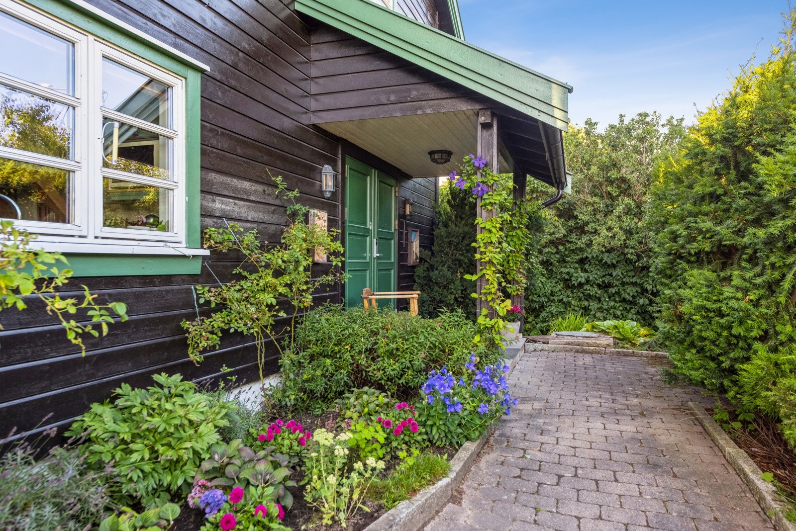 Tomten er frodig og skjermet, med flotte blomsterbed, frukttrær og bærbusker Galleribilde