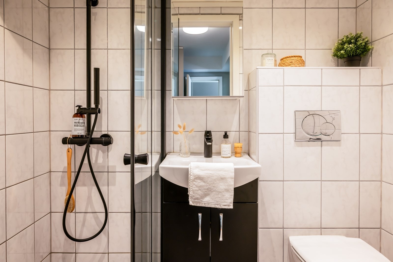Delikat baderom med lekker dusjløsning, pen innredning og vegghengt toalett. Galleribilde