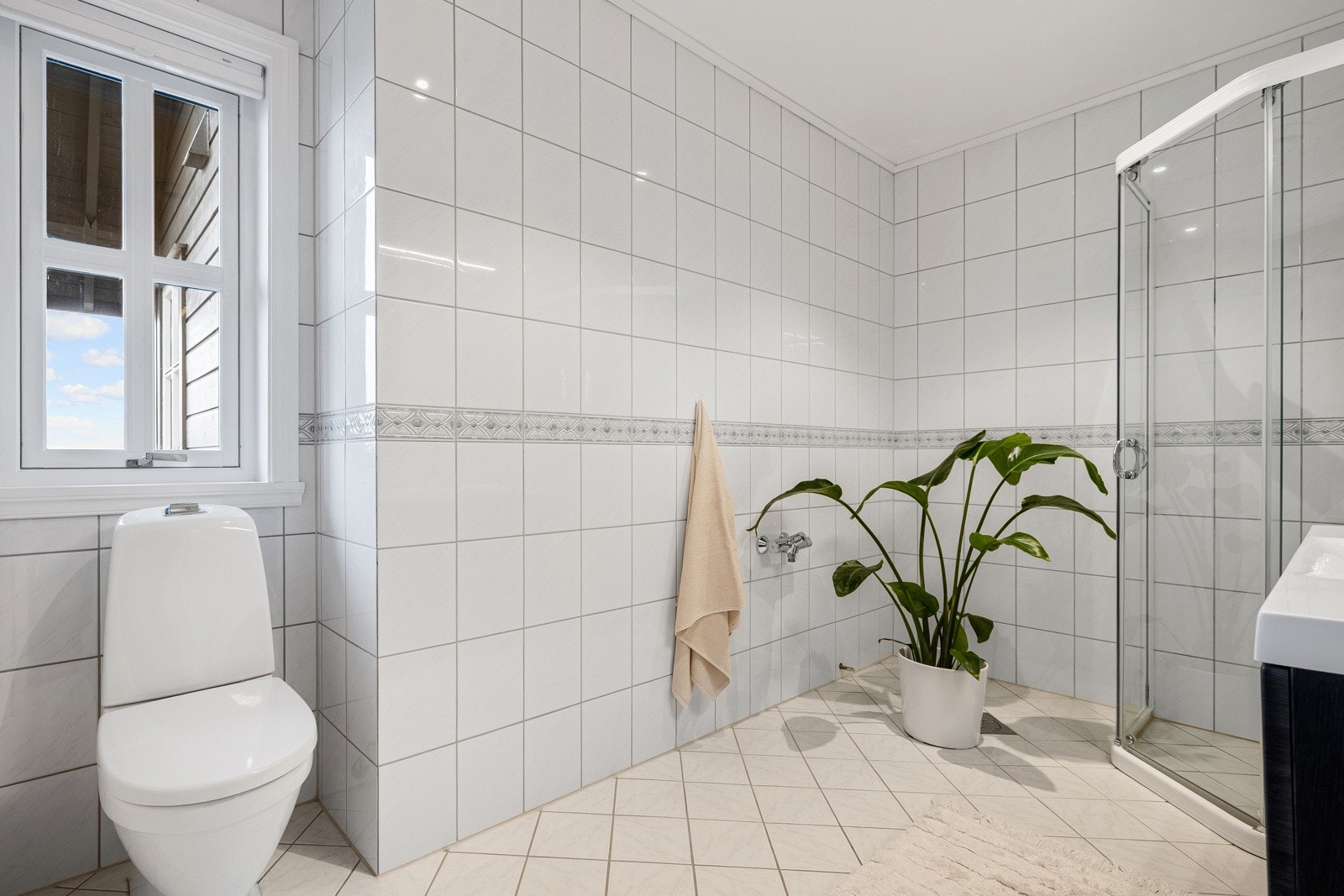 Badet har speilskap med overlys, dusjhjørne med glassdører, vegghengt dusjarmatur og gulvstående toalett. Galleribilde