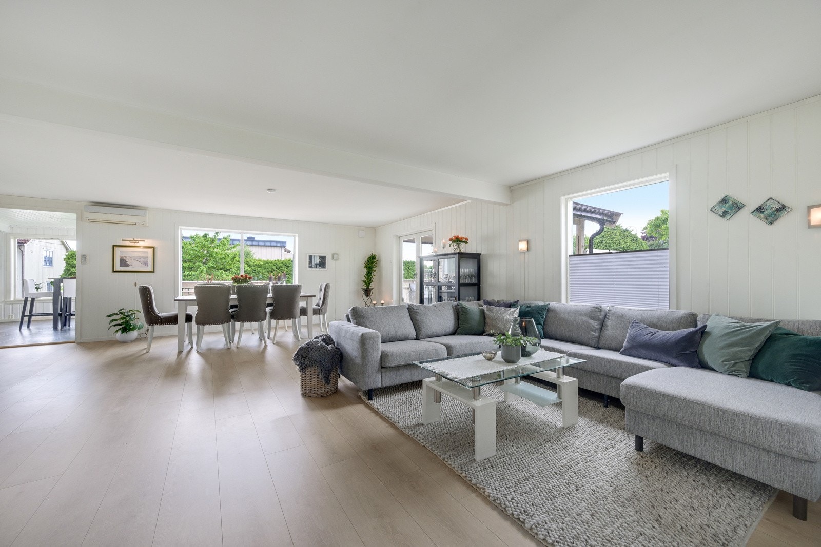 Stor og lys stue med pent gulv og vinduer både mot syd og vest Galleribilde