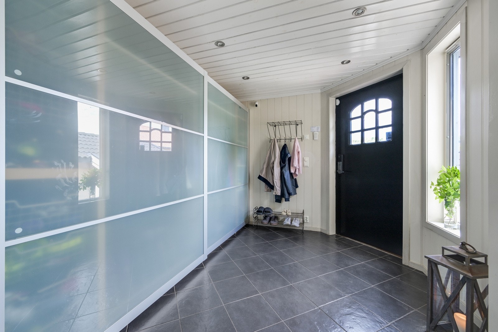 Romslig vindfang med fliser og stor skyvedørsgarderobe Galleribilde