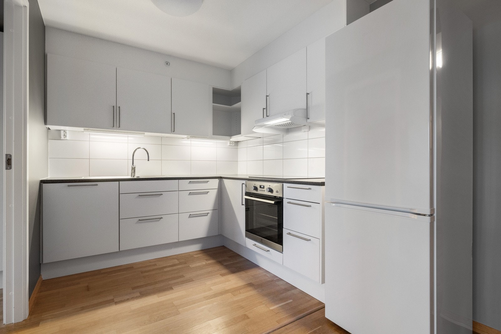 Kjøkkenet holder et tidløst preg med sine lyse slette fronter Galleribilde