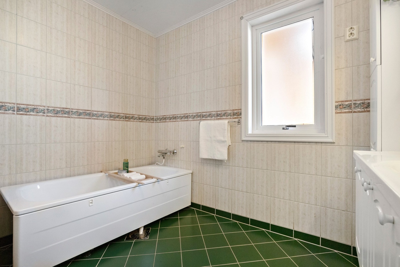 Baderom med dusjkabinett og badekar, hvite skapfronter og fliser på gulvet. Galleribilde