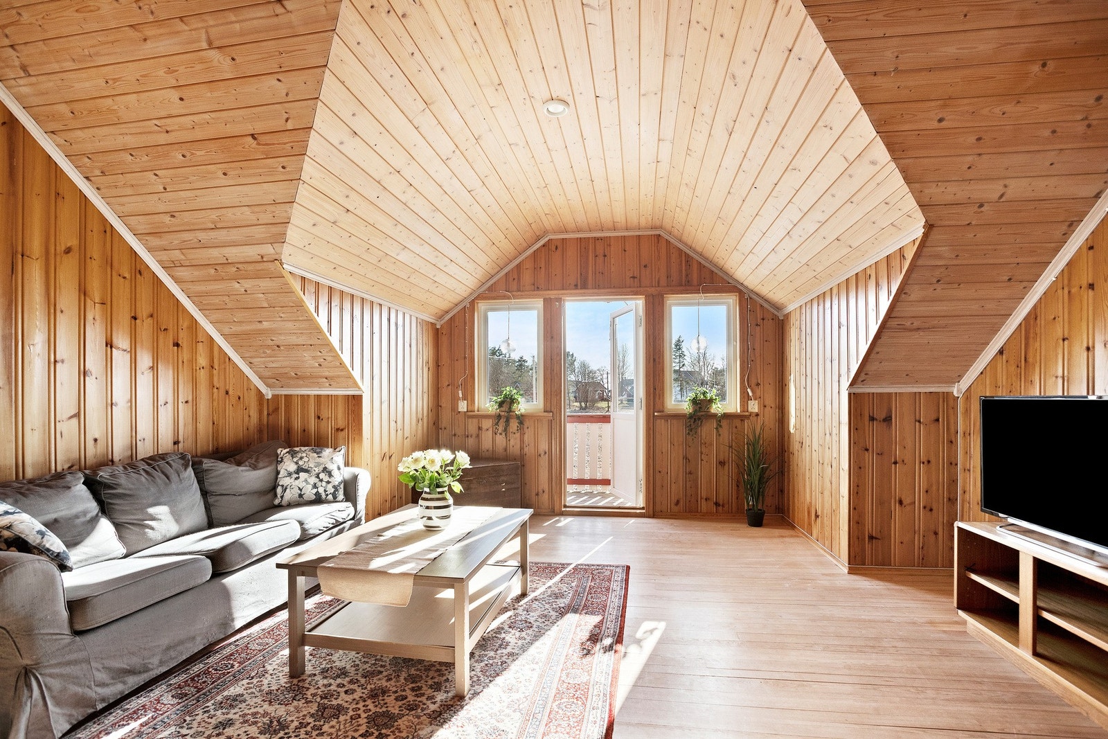 Romslig loftstue med tregulv og panelvegger. Utgang til balkong. Galleribilde