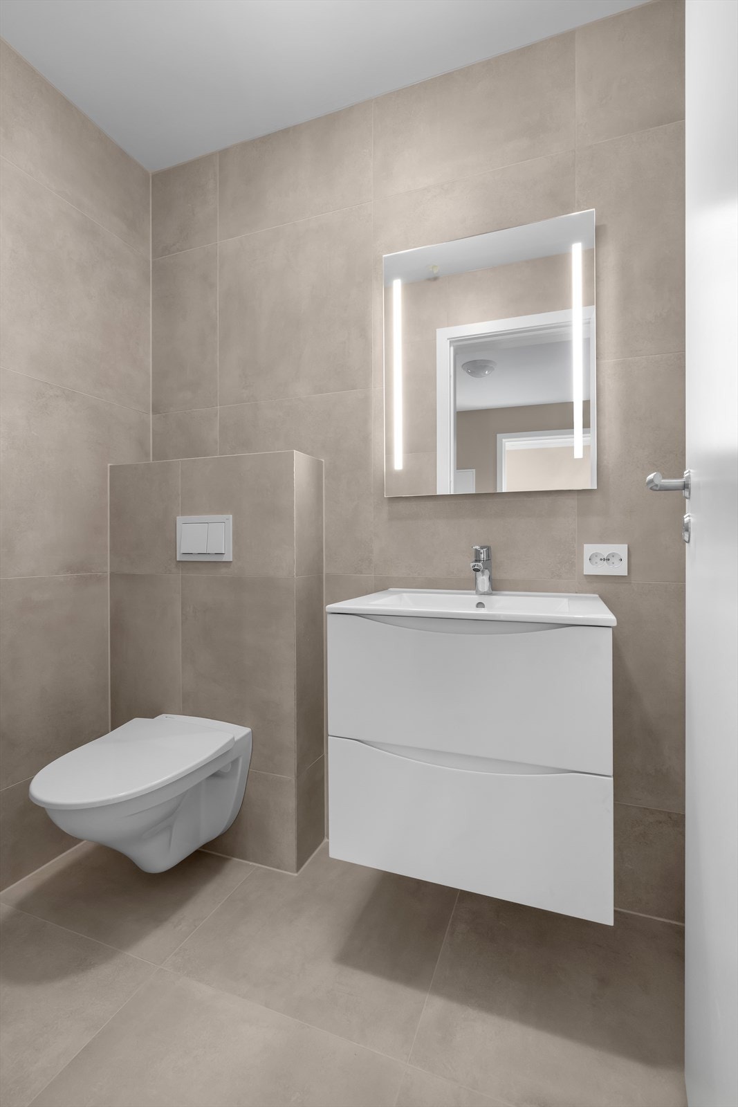 Flott flislagt bad innredet med vegghengt toalett, nedfelt servant og speil. Bildene er tatt fra en tilsvarende bolig, og avvik kan forekomme Galleribilde