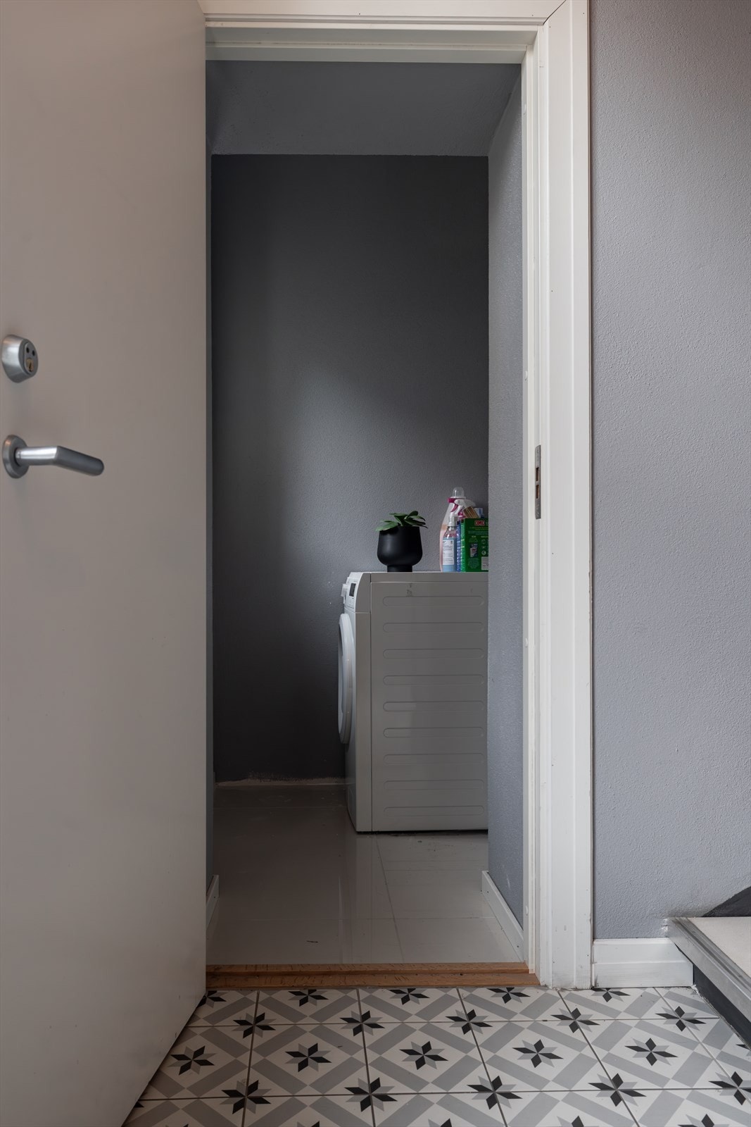 Praktisk kott i trappegangen med flislagt gulv og opplegg for vaskemaskin. Galleribilde