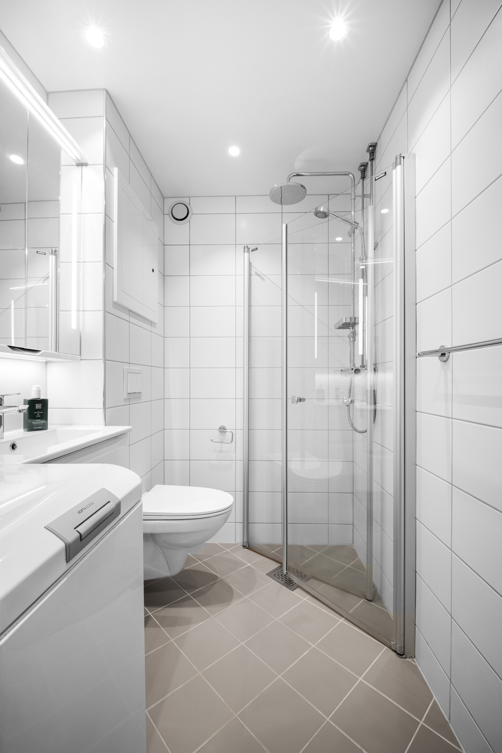 Badet er videre utstyrt med et vegghengt toalett, opplegg for vaskemaskin og et dusjhjørne med innfellbare glassdører Galleribilde