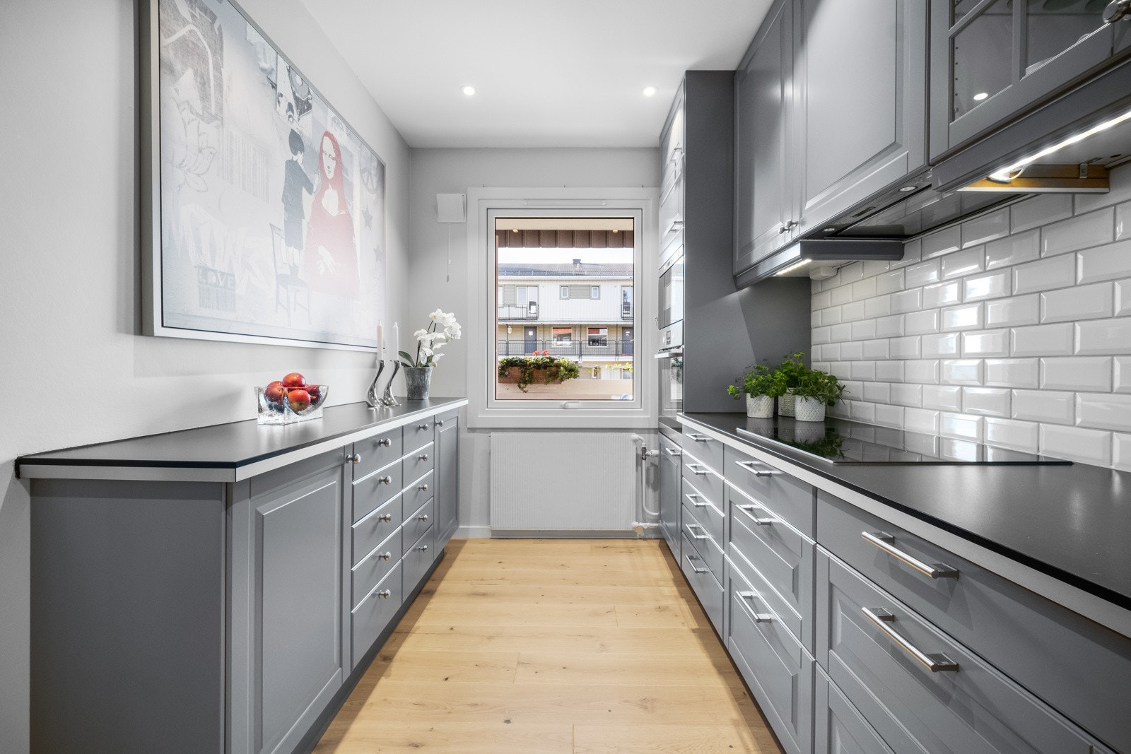 Innredningen fra Ikea har grå, profilerte fronter, vitrinedører, takhøye skap og sort laminatbenkeplate med nedfelt kum i stål Galleribilde