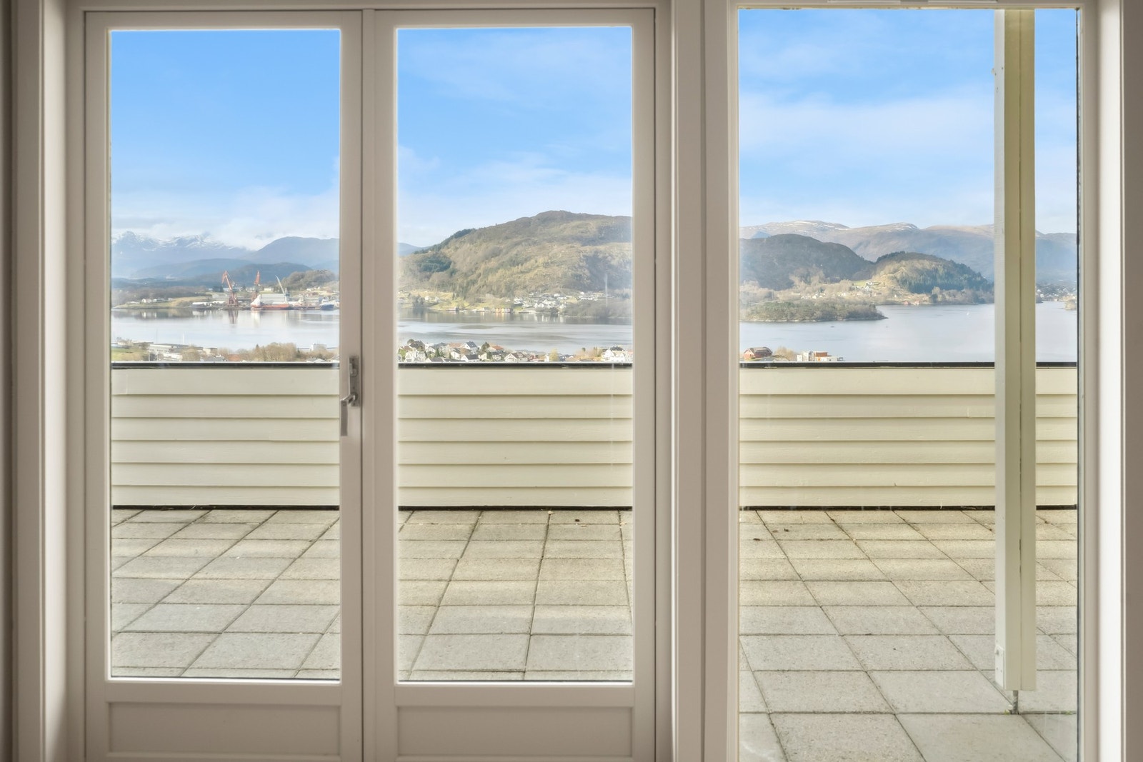 Tofløyet verandadør og store vindusflater mot sørvest slipper inn rikt med naturlig lys, og gjør at den fantastiske utsikten kommer til sin rett. Galleribilde