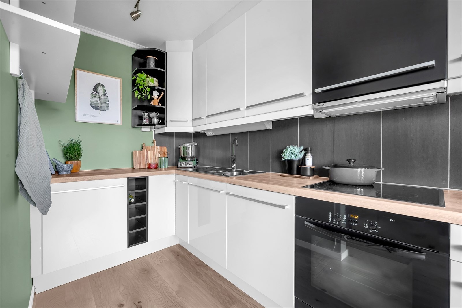 Kjøkkeninnredning med lyse, glatte fronter, fliser på vegg over kjøkkenbenk og heltre benkeplate. Galleribilde