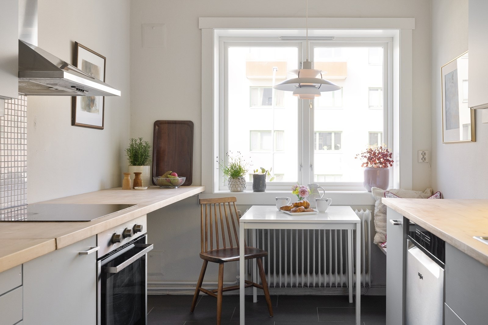 Kjøkkeninnredning med glatte, malte fronter, fliser på vegg over kjøkkenbenk og benkeplate i tre. Galleribilde