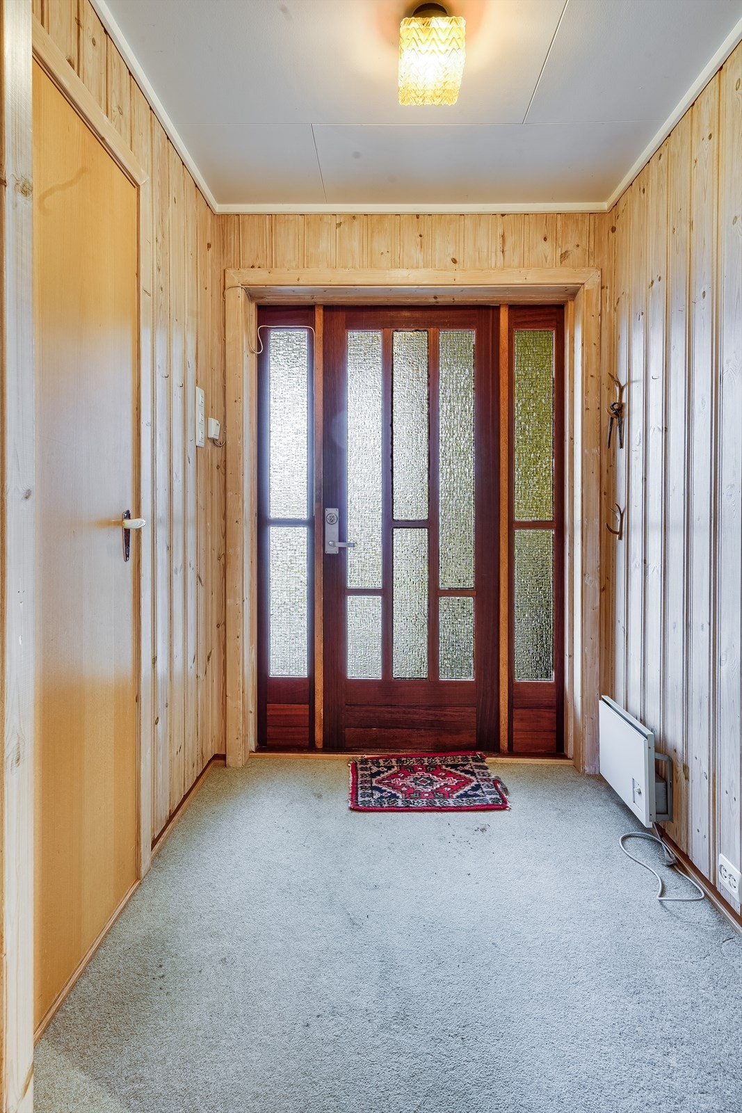 Du ønskes velkommen inn i et vindfang, ytterdør med glassfelt. Galleribilde