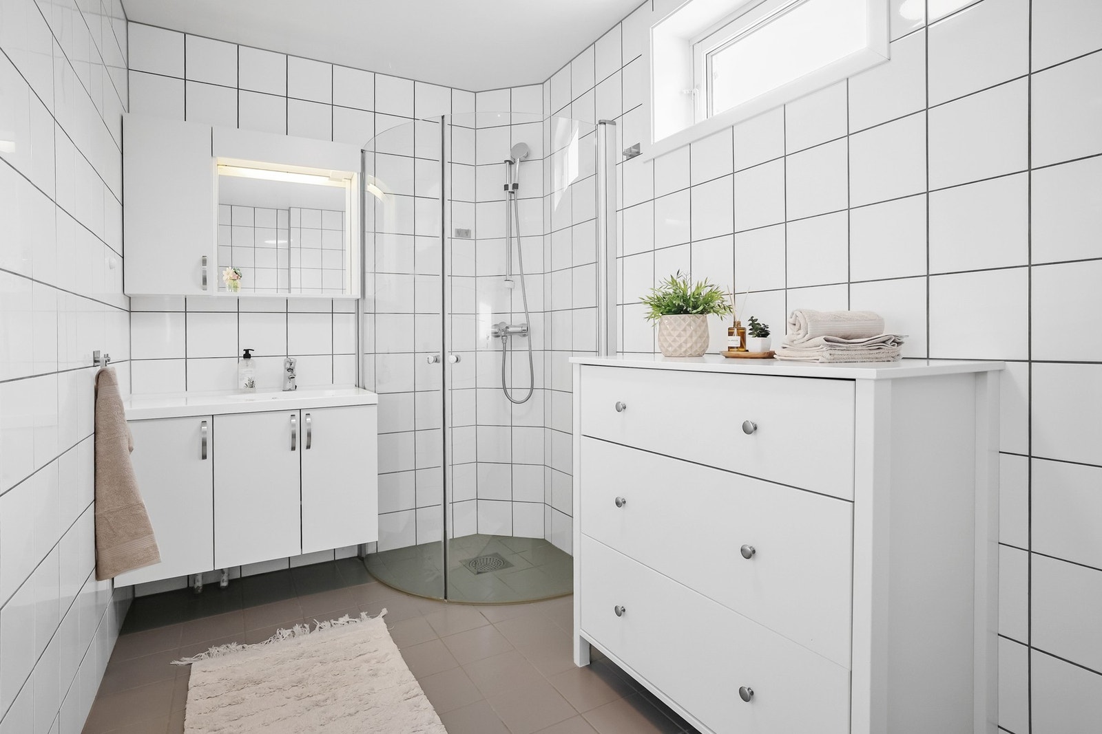 Det er vegghengt møblement ved speil med overlys og stikk-kontakt. Galleribilde