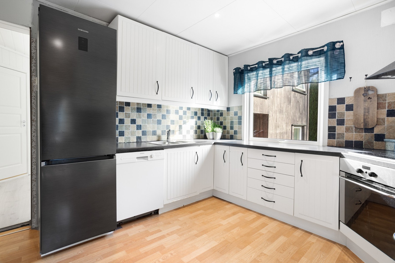 Kjøkken med innredning som har godt med skap-og benkeplass. Det er integrert stekeovn med platetopp, opplegg for oppvaskmaskin og plass for frittstående kjøl/fryseskap. Galleribilde