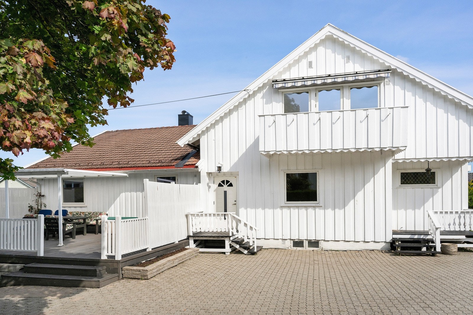 Steinbelagt gårdsplass ved inngangspartiene. Terrasse med pergola ved siden av. Galleribilde