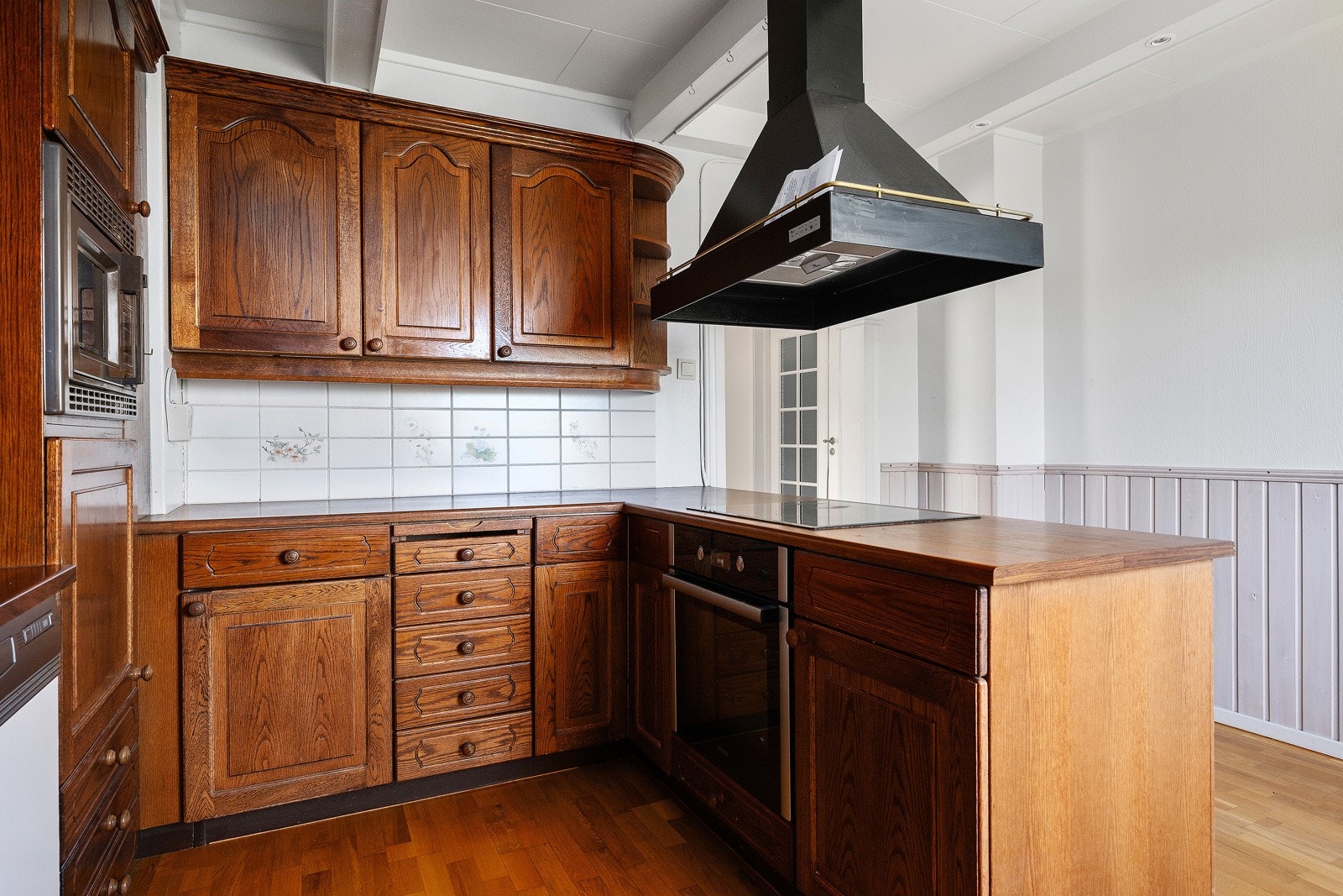 I dag har kjøkkenet innredning med profilerte fronter, fliser på vegg og laminat benkeplate med kum. Galleribilde