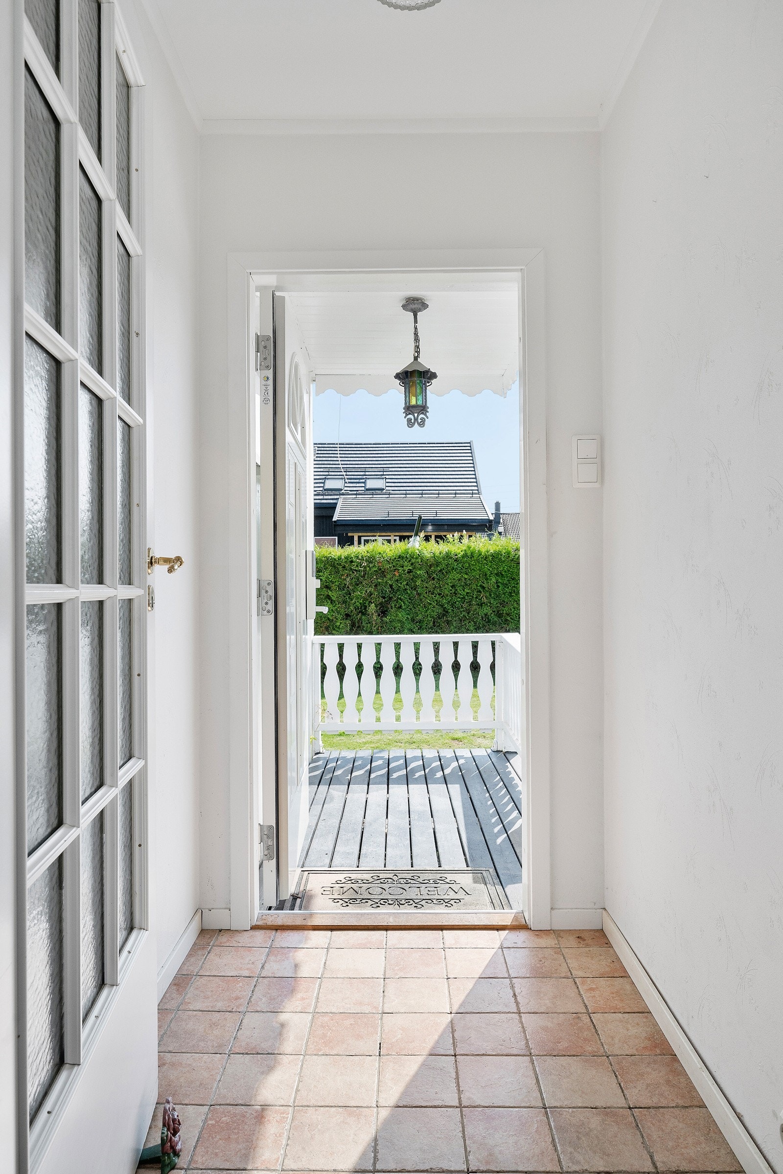 Adkomst via en overbygd terrasse og et flislagt vindfang. Galleribilde