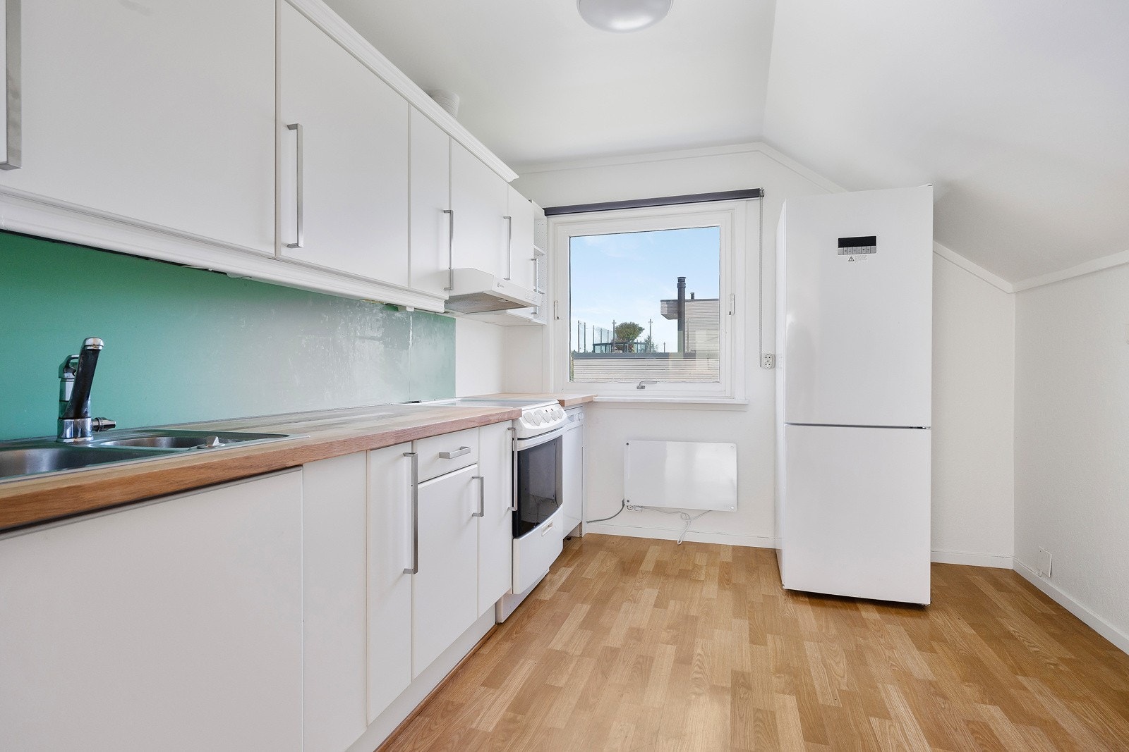 Kjøkkenet ligger i et eget rom og har i dag innredning med lyse, glatte fronter og heltre benkeplate med dobbel stålkum. Galleribilde