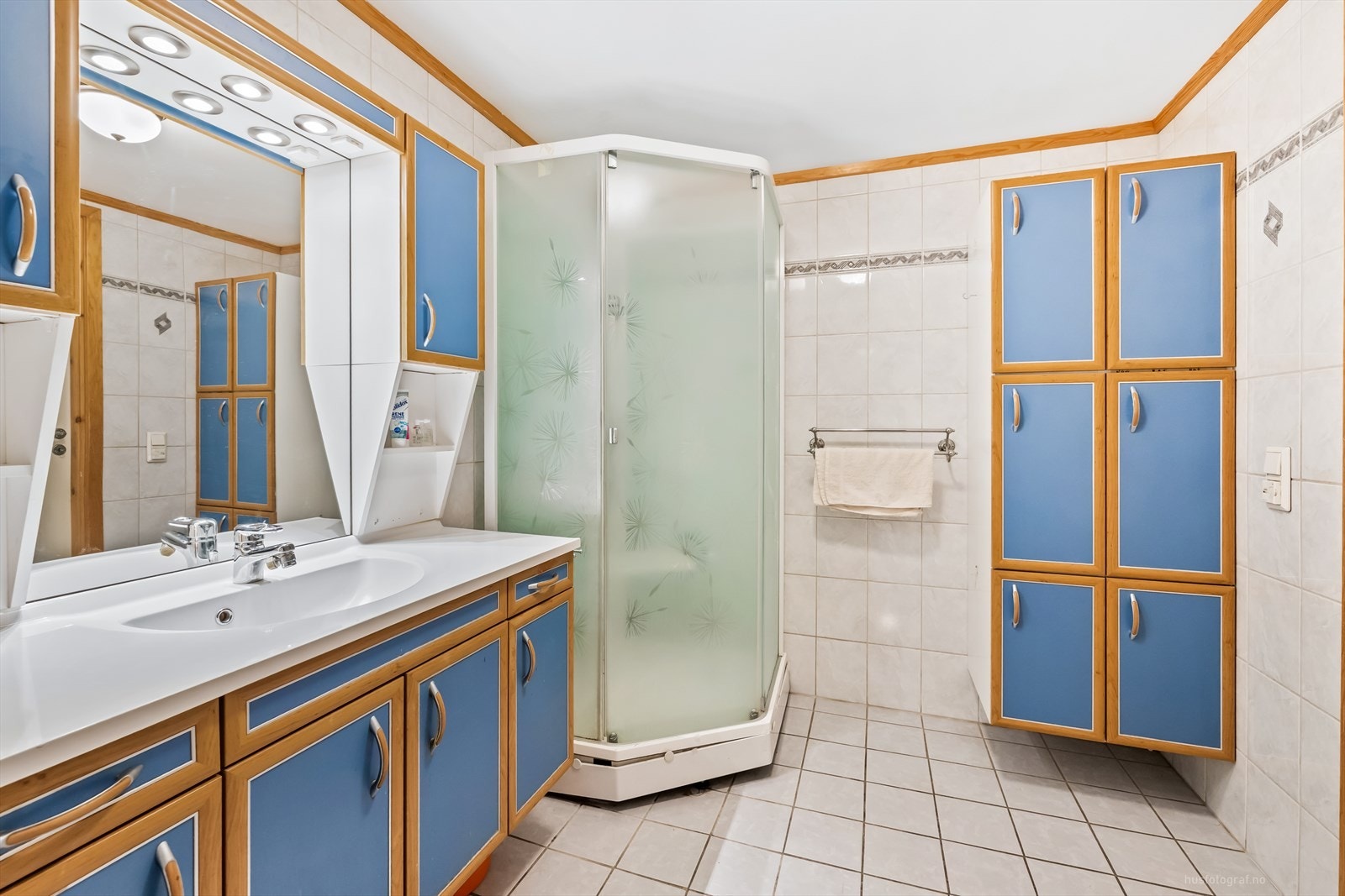 Pent flislagt bad med innredning bestående av klosett, dusjhjørne og baderomsinnredning med speilskap. Galleribilde