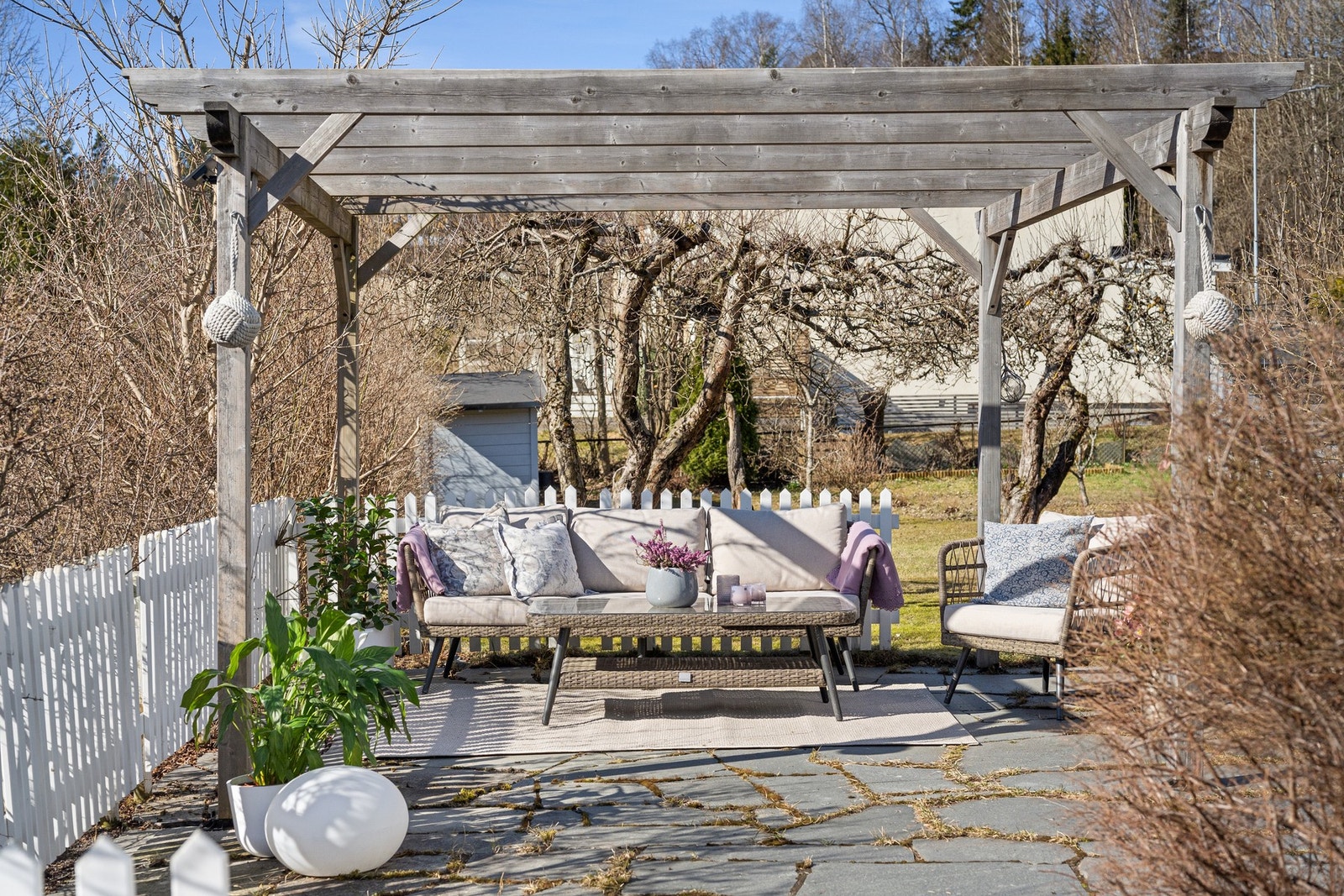 Boligen har en ekstra hyggelig hage og skiferlagt uteplass med pergola Galleribilde