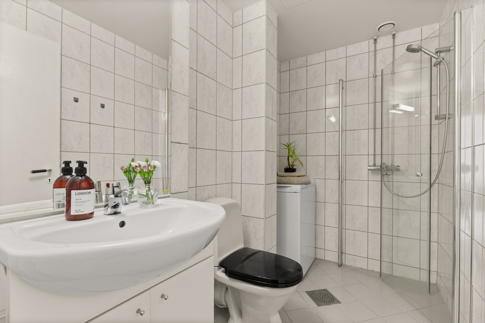 Badet er utstyrt med dusj med innfellbare glassvegger, servant med skap, speil med lys, gulvmontert wc og opplegg for vaskemaskin. Galleribilde