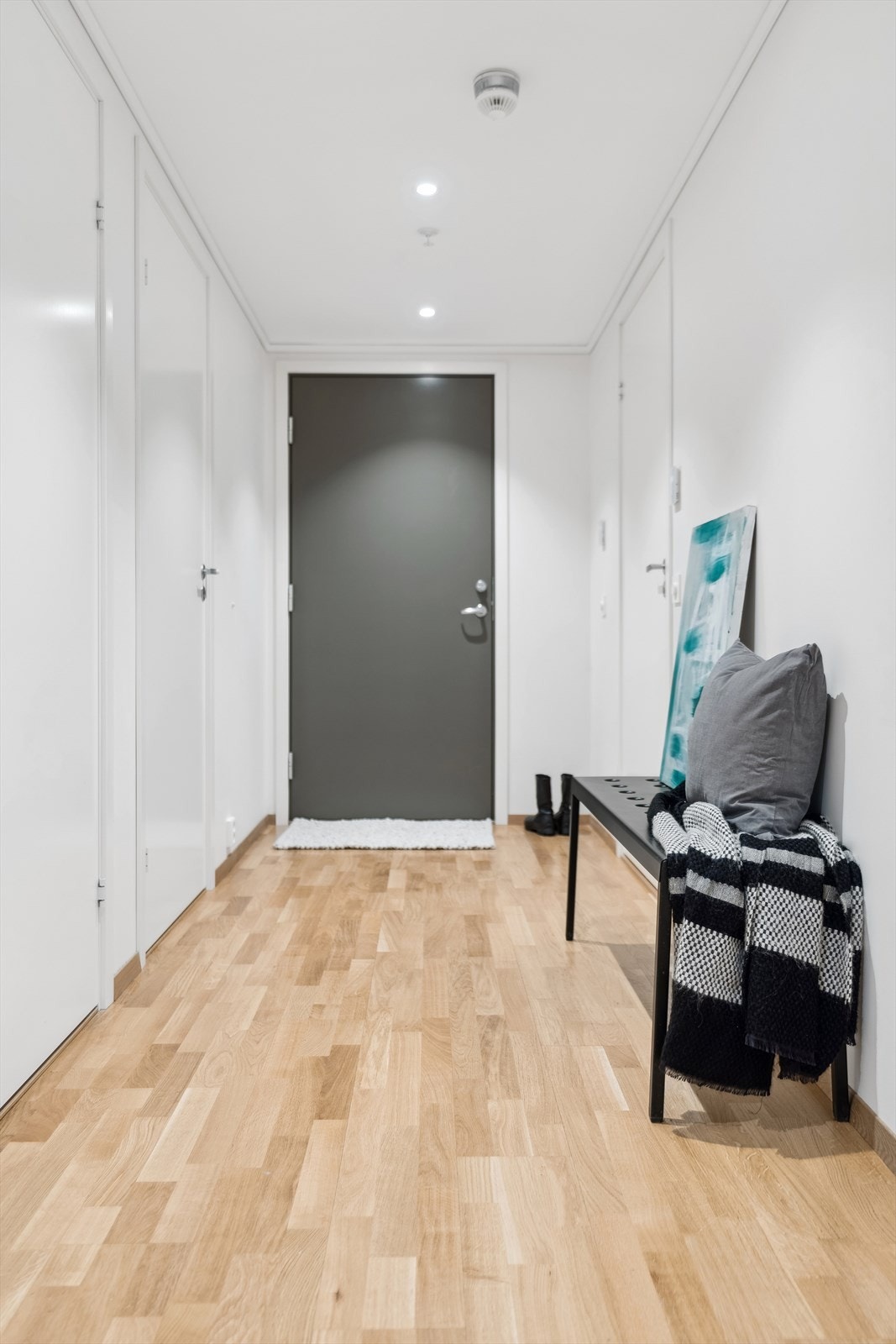 Man kommer inn i en hyggelig entré med hvitmalte overflater og belysning med downlights - Her er det godt å komme hjem og hyggelig å ønske gjester velkommen Galleribilde