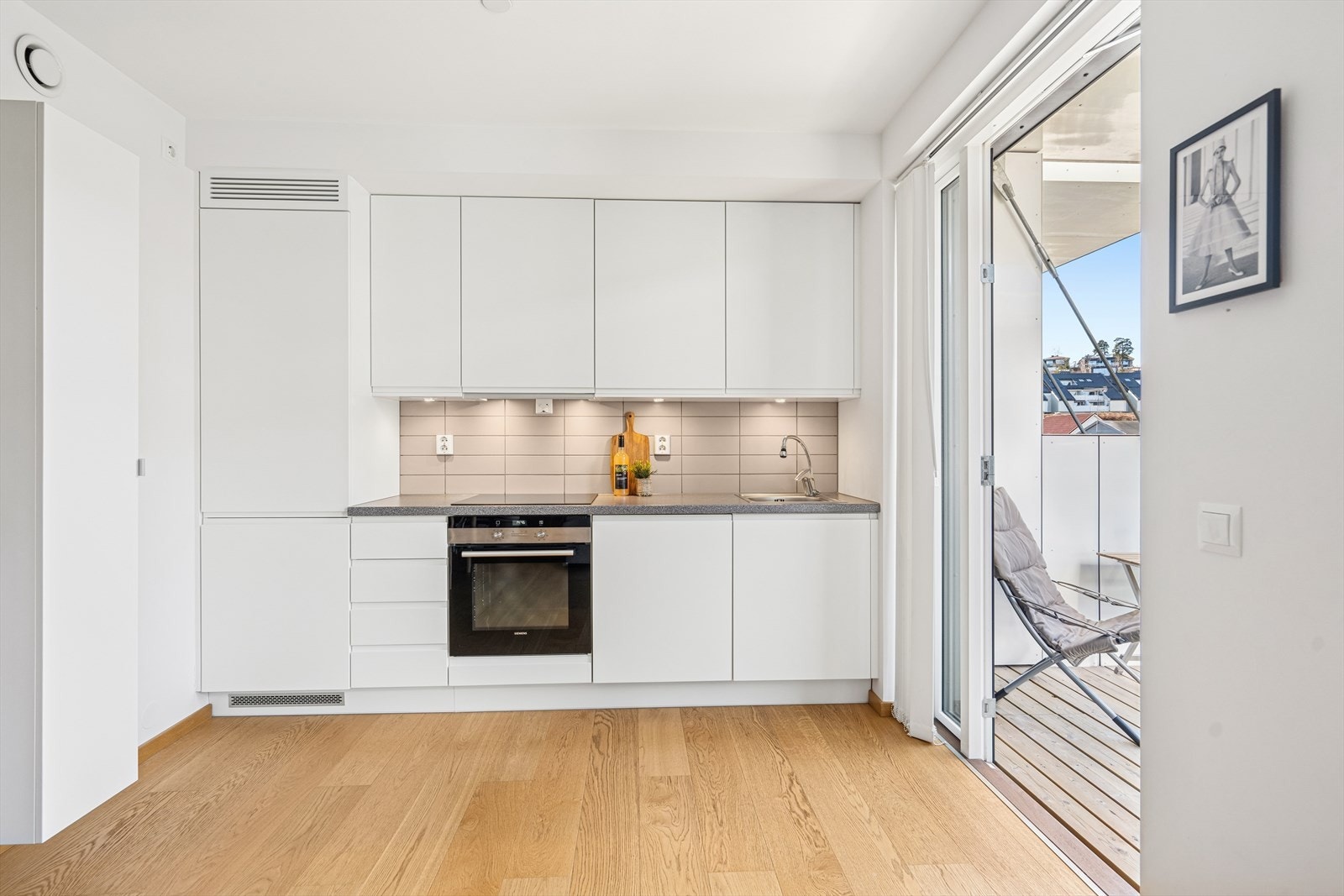 Kjøkkenet har en stilren og lekker utførelse med slette, hvite fronter. Galleribilde