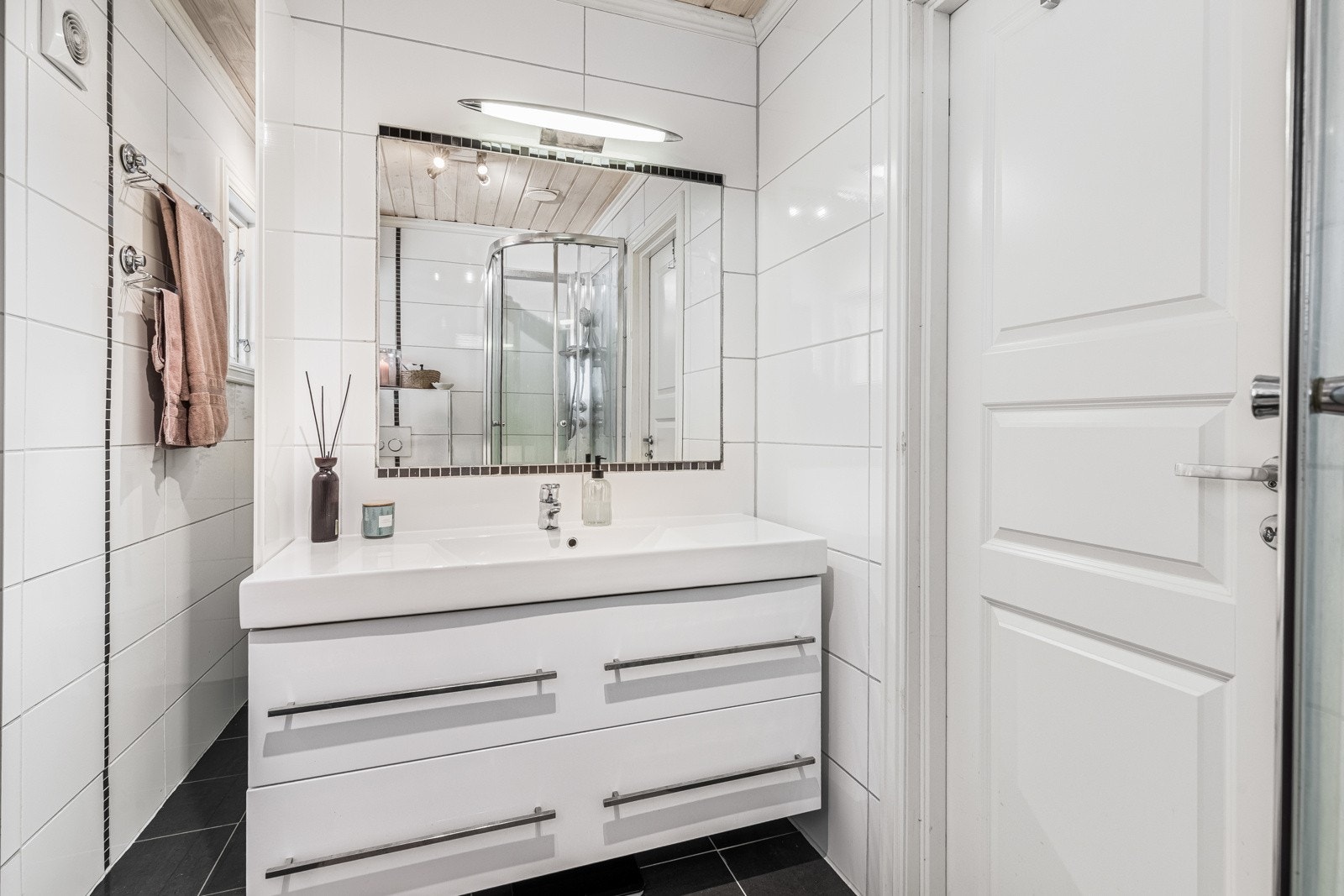 I første etasje ligger boligens bad, et delikat rom fra 2013 med flislagte overflater, gulvvarme, spotter på skinne i himlingen og mekanisk avtrekk. Galleribilde