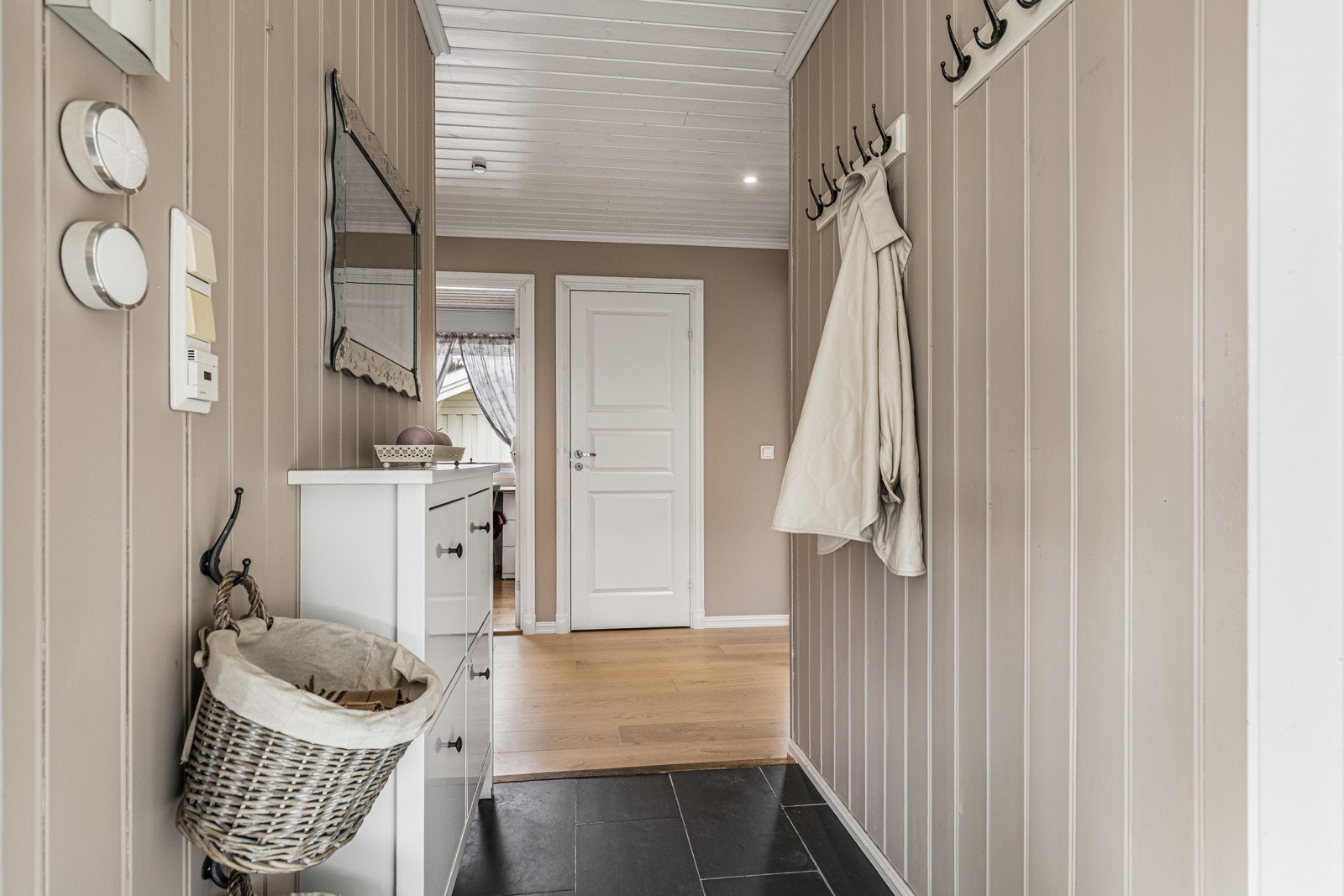 Entreen er et hyggelig rom å komme hjem til med sorte gulvfliser, harmonisk farge på veggepanelet og varmekabler i gulvet. Galleribilde