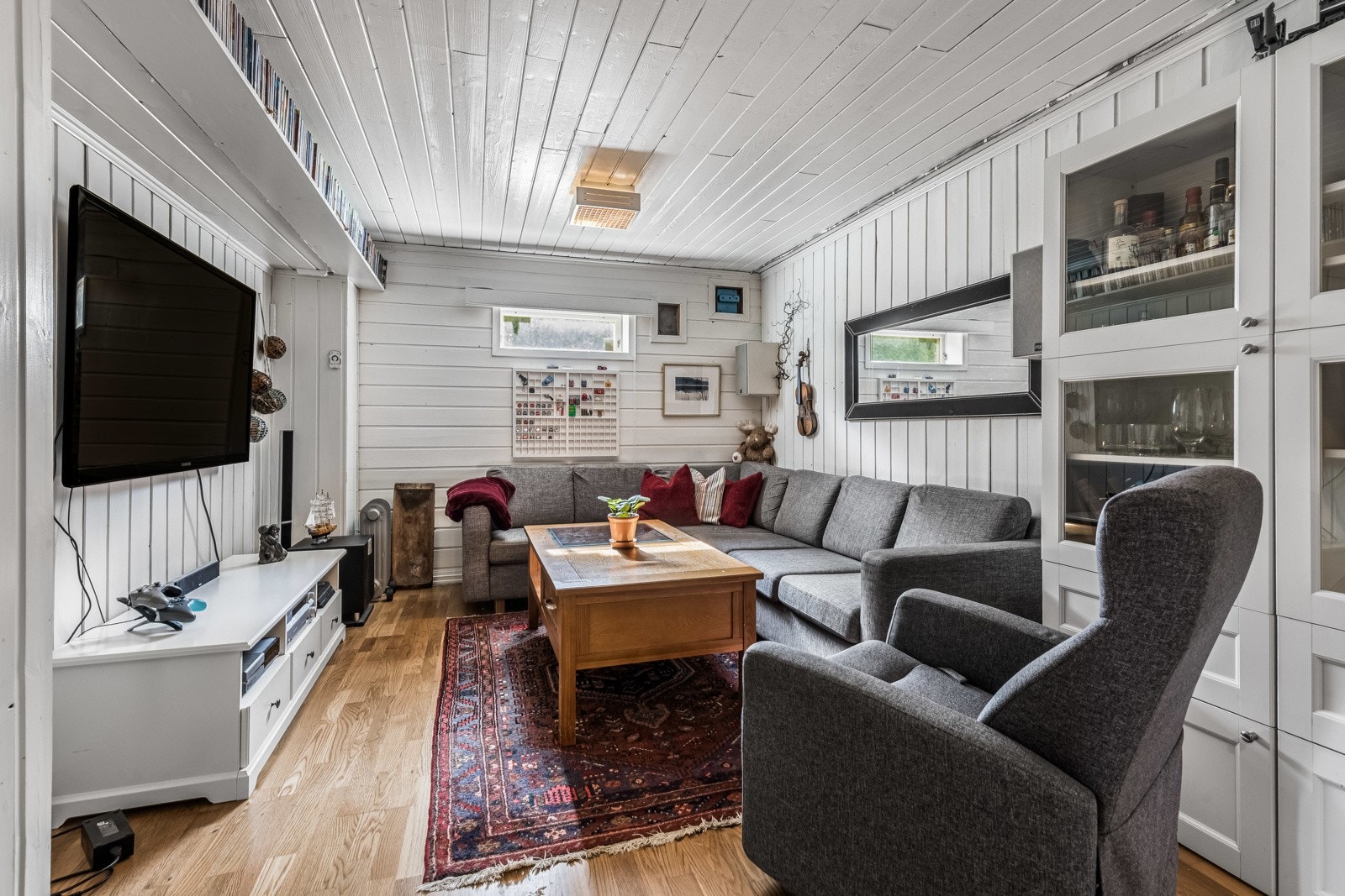 Kjellerstuen er et trivelig rom med høytsittende vindu, hvitmalt panel på alle vegger og en praktisk hylle montert høyt på den ene veggen. Rommet er ikke bruksendret. Galleribilde